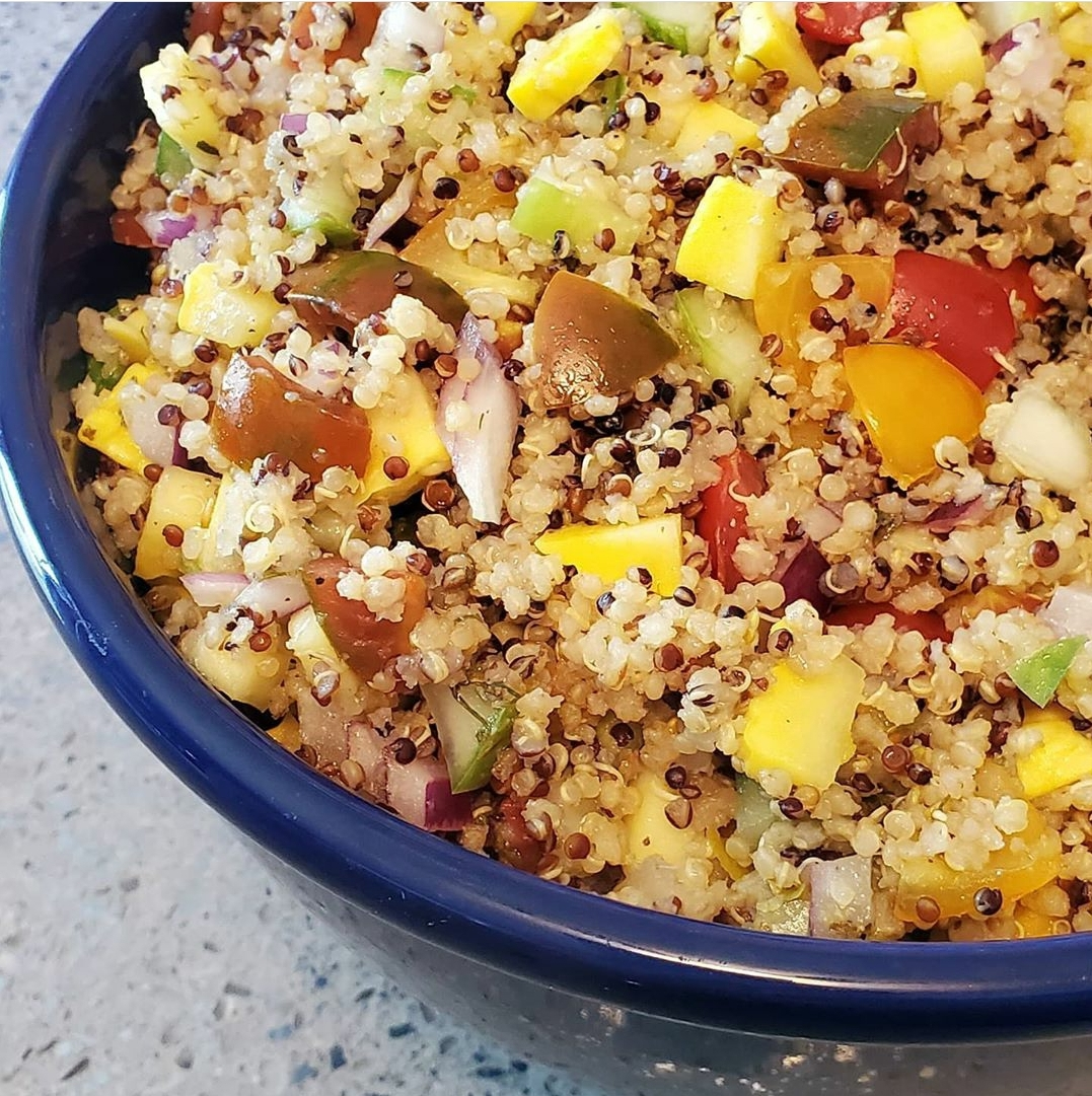 Colorful quinoa salad with diced vegetables, including bell peppers and onions, in a deep blue bowl. A fresh, nutritious dish for healthy meals.